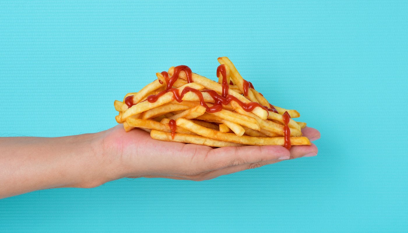 une main remplie de frites ketchup