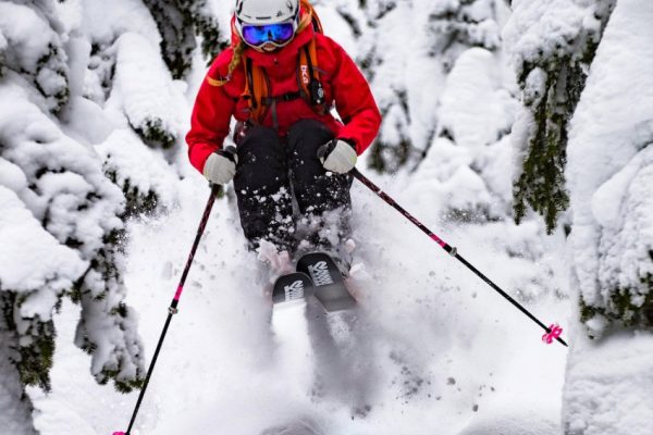 Amie Engerbretson en backcountry dans la poudreuse entre forêt et barre rocheuse