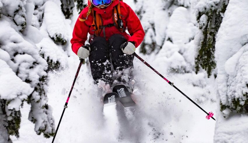 Amie Engerbretson en backcountry dans la poudreuse entre forêt et barre rocheuse