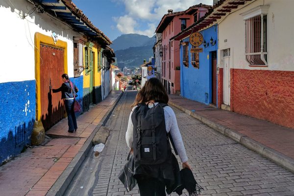 Une backpackeuse de dos dans une rue colorée