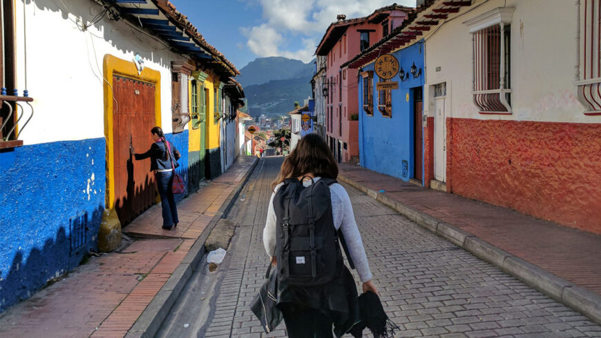 Une backpackeuse de dos dans une rue colorée