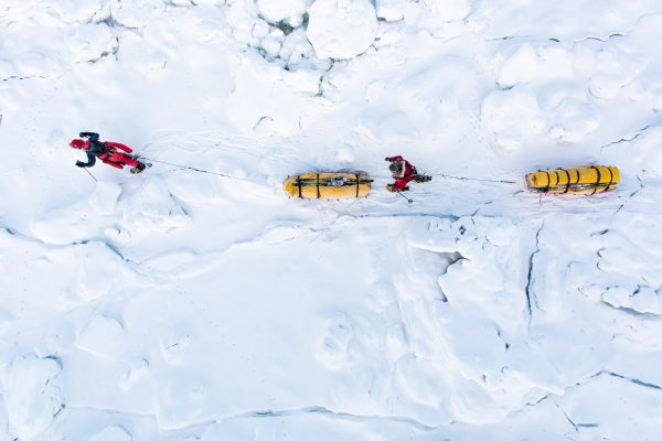 Deux personnes tirent des traîneaux sur la neige