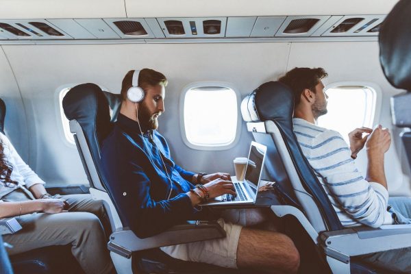 Un hipster portant un casque travaille sur son ordinateur dans un avion