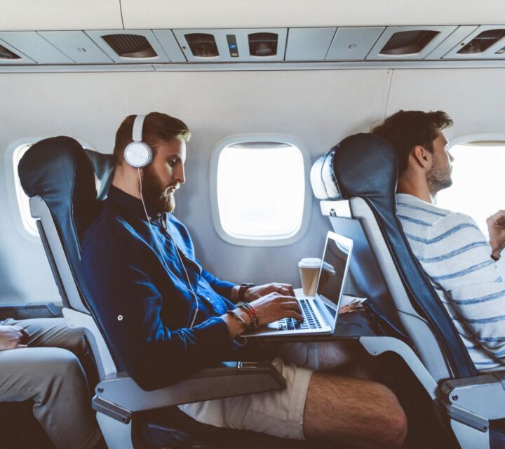 Un hipster portant un casque travaille sur son ordinateur dans un avion