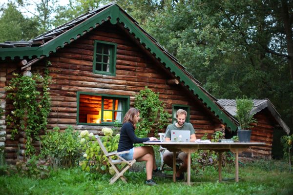 Un couple travaille dehors devant un gîte en bois