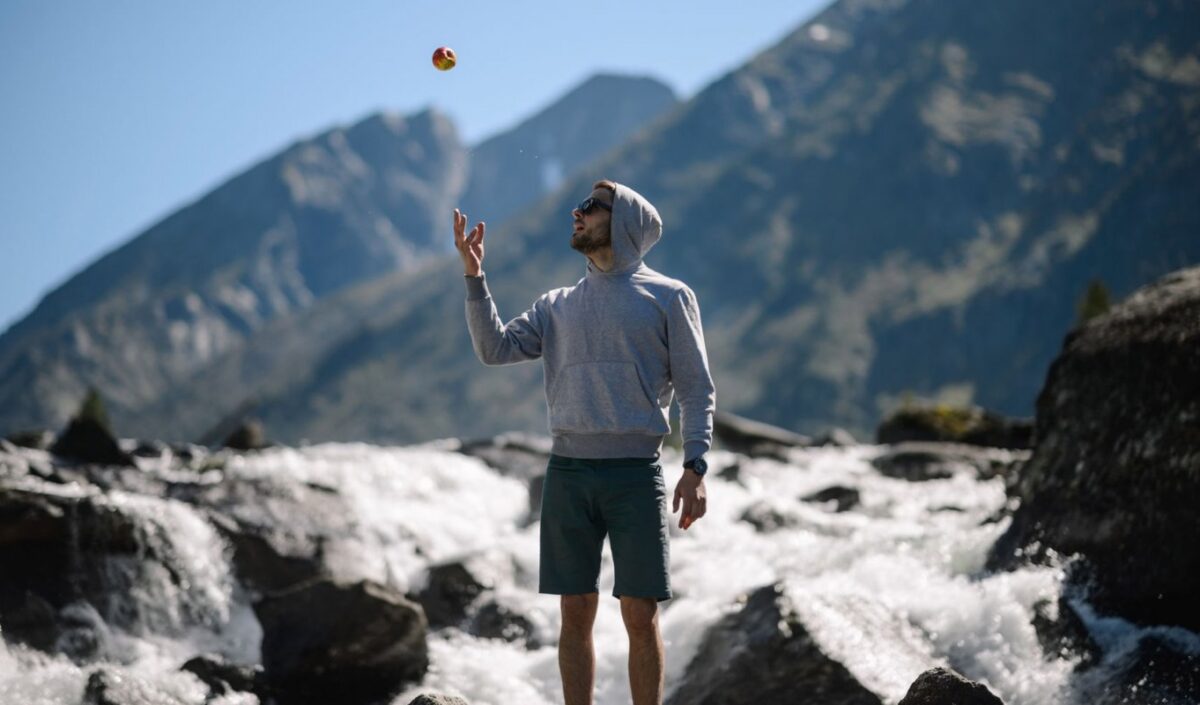 Un homme devant un torrent lance une pomme en l'air