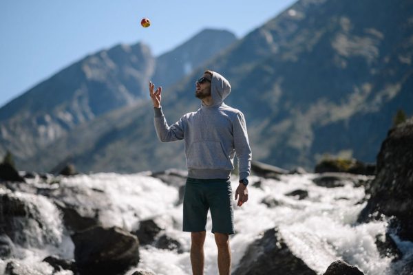 Un homme devant un torrent lance une pomme en l'air