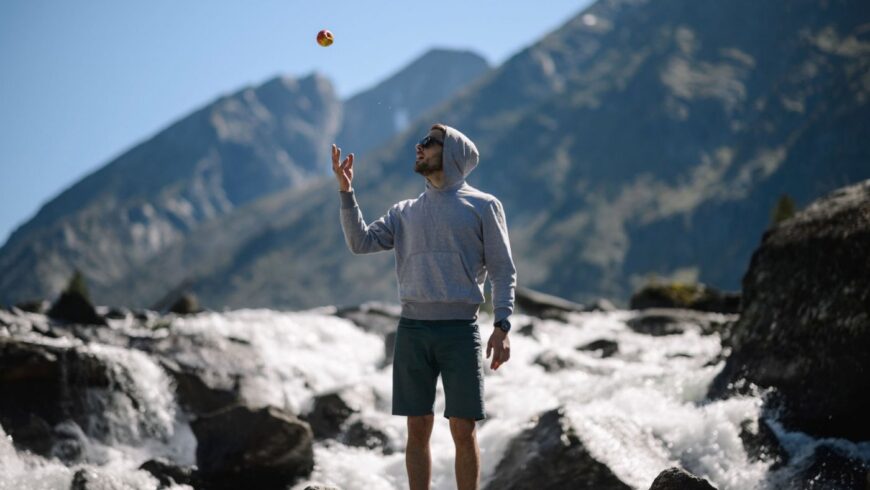 Un homme devant un torrent lance une pomme en l'air