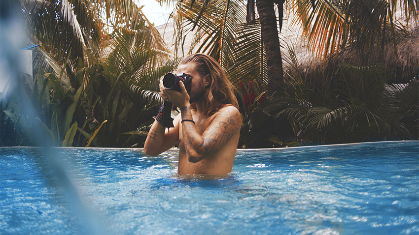 Un hispter tatoué prend des photos dans une piscine à Bali