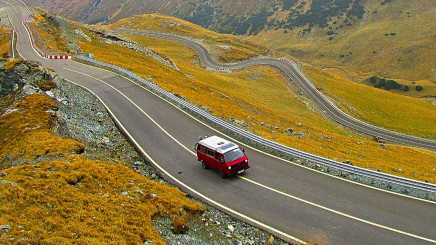 Un Van rouge roule sur une route de montagne