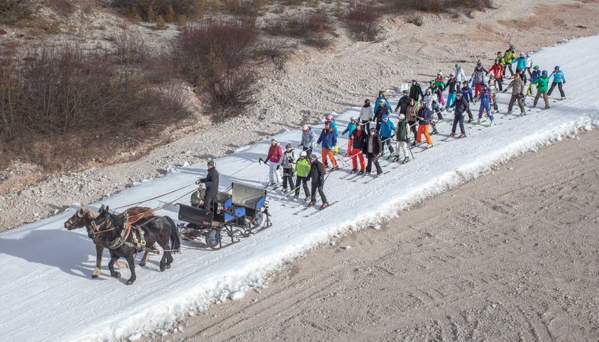 Stationde de ski Armentarola - Lagazuoi - District of Bolzano, Italy - August 23 2018. Un groupe de touristes est tiré par un traîneau le long du lit d'une rivière, enneigé artificiellement.