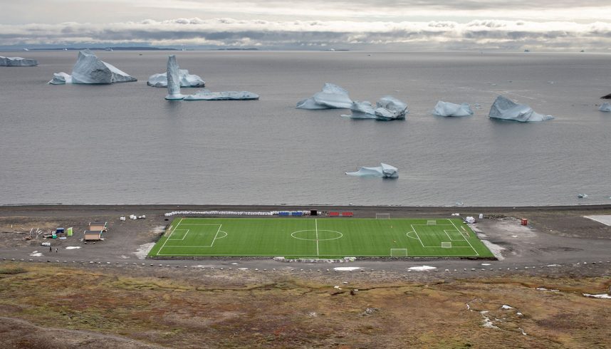 Qeqertarsuaq, île Disko, Groenland - 27 août 2018. Le stade synthétique Qeqertarsuaq avec un iceberg à l'arrière. En raison de la basse température, le championnat de football du Groenland se joue en seulement une semaine. Qeqertarsuaq est un port et une ville de la municipalité de Qeqertalik, située sur la côte sud de l'île Disko (côte ouest du Groenland). Fondée en 1773, la ville abrite aujourd'hui un campus de l'Université de Copenhague connu sous le nom de Station Arctique.