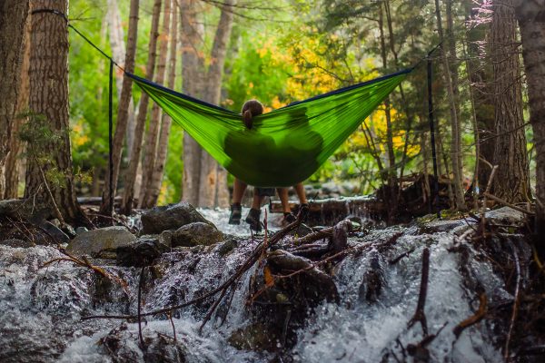 Deux personnes se reposant au dessus d'une rivière en forêt