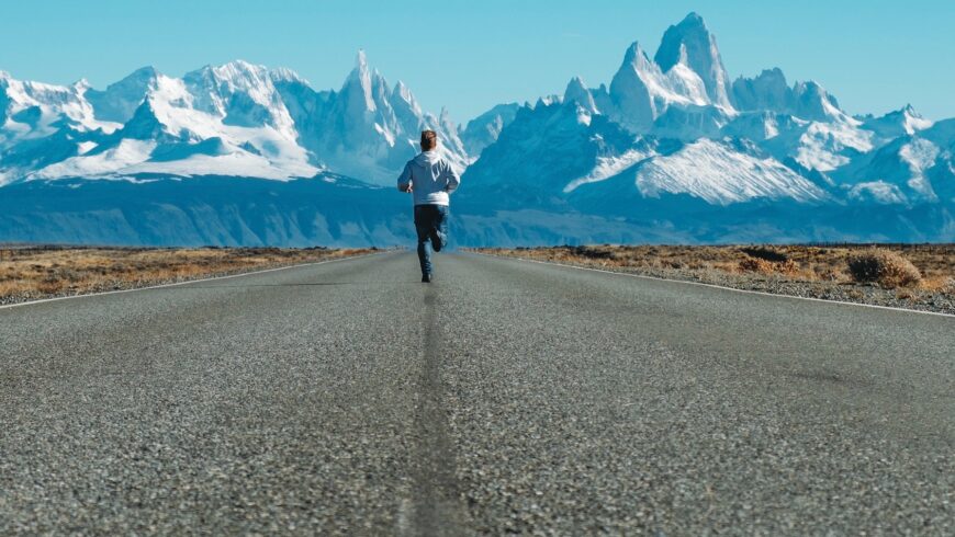 homme courant sur la route vers des montagnes enneigées Andrea Leopardi/Unsplash