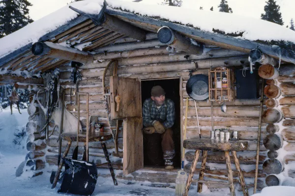 Dick Proenneke devant la porte de sa cabane en rondin en alaska