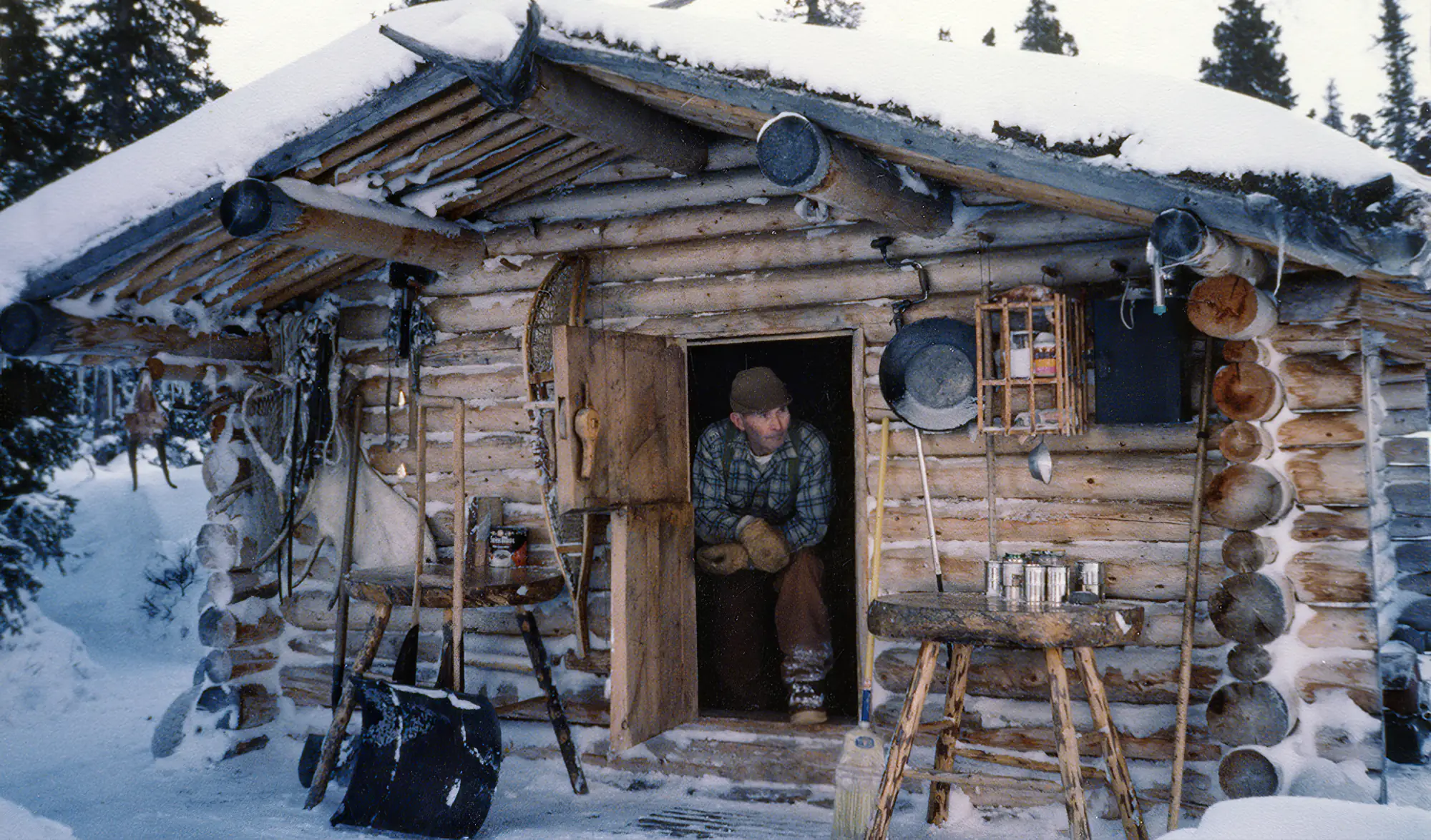 Dick Proenneke devant la porte de sa cabane en rondin en alaska