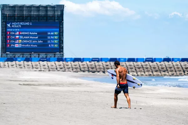 Surfeur de l'équipe de France au JO de Tokyo sur la plage avec sa planche de surf à la main