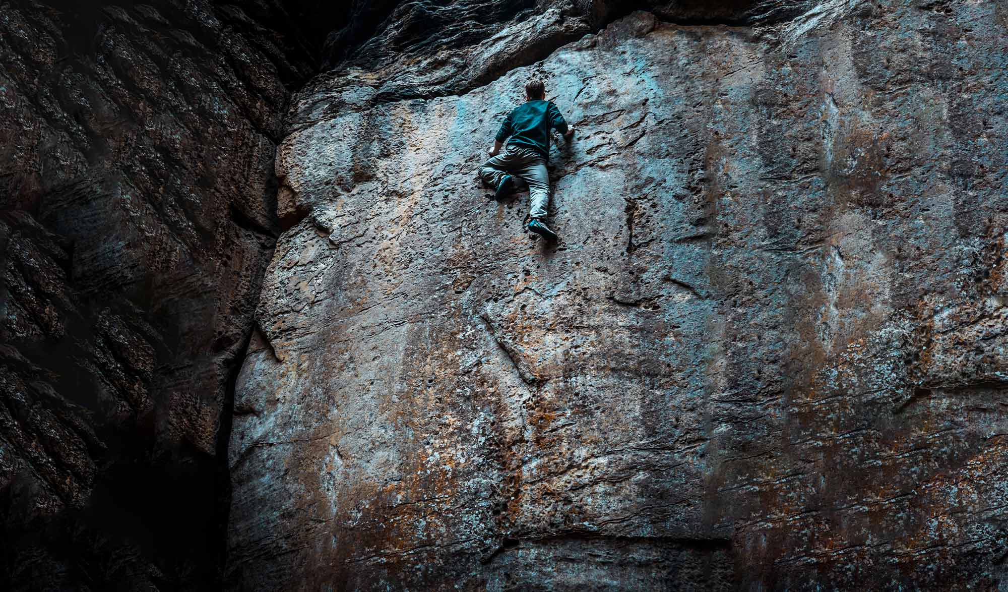 grimpeur en free solo sur un mur sombre