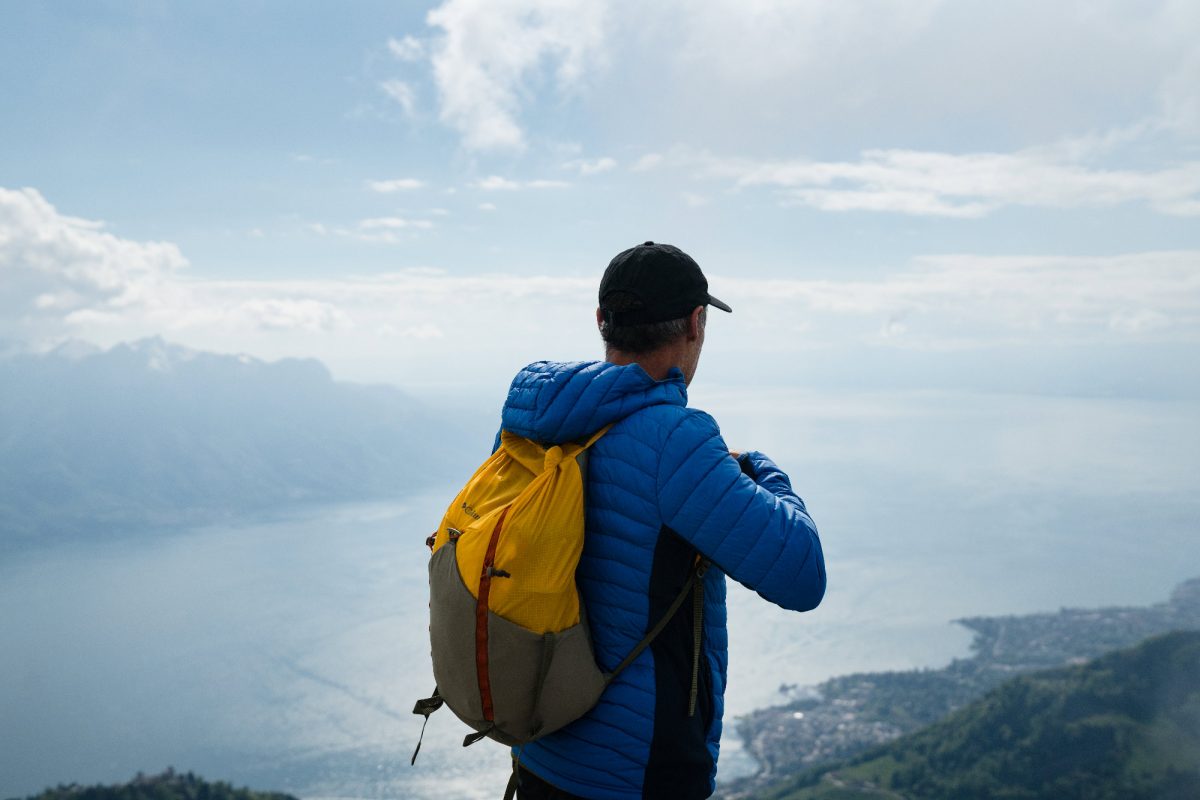 Mike Horn de dos avec vue sur un lac suisse en contrebas