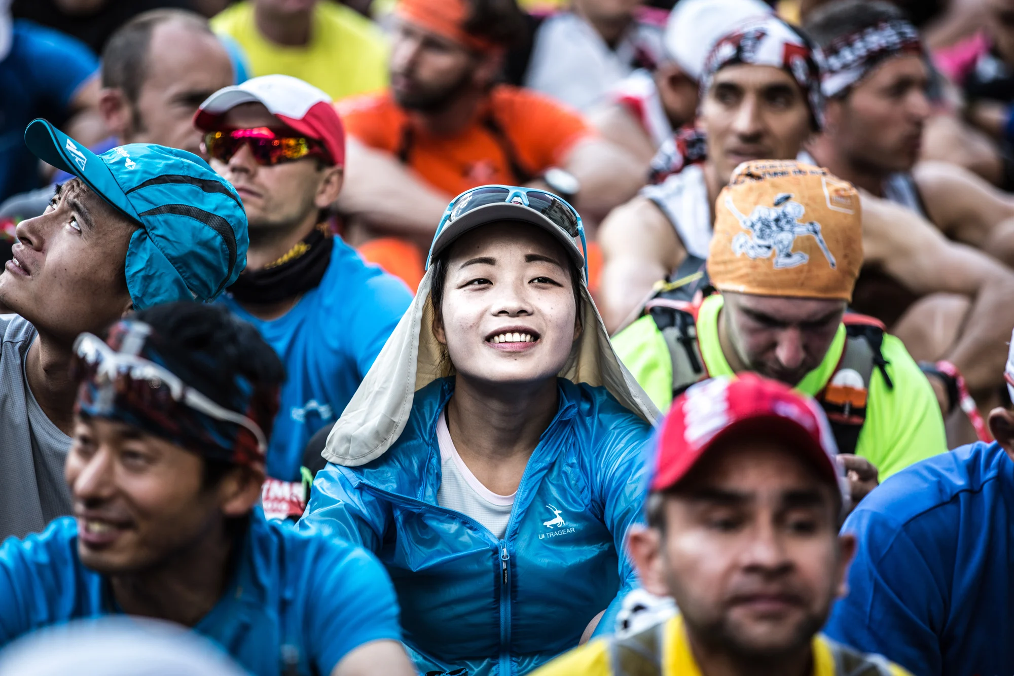 coureuse asiatique de l'UTMB assise dans la raquette de départ au milieu des autres participants