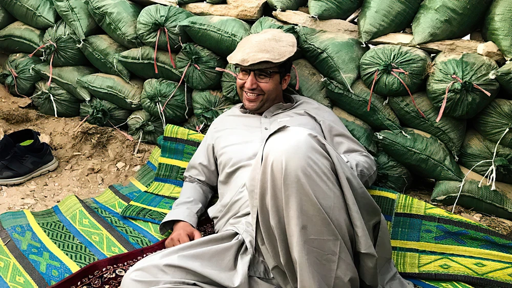 Aziz Tassal couché devant des sacs de sable