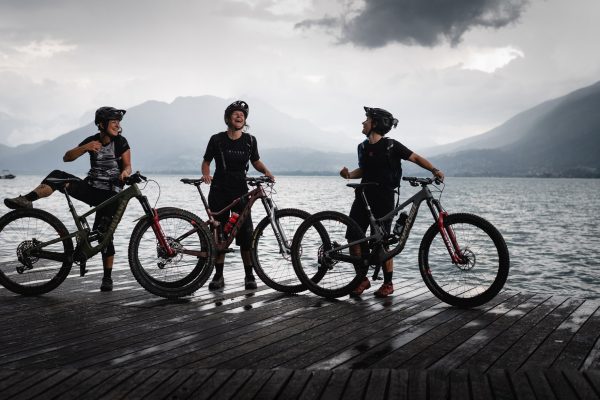 3 rideuses sur un ponton d'Annecy avec leur VTT