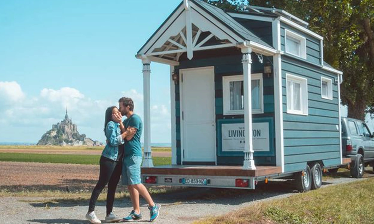 couple devant tiny house avec mont saint michel derriere