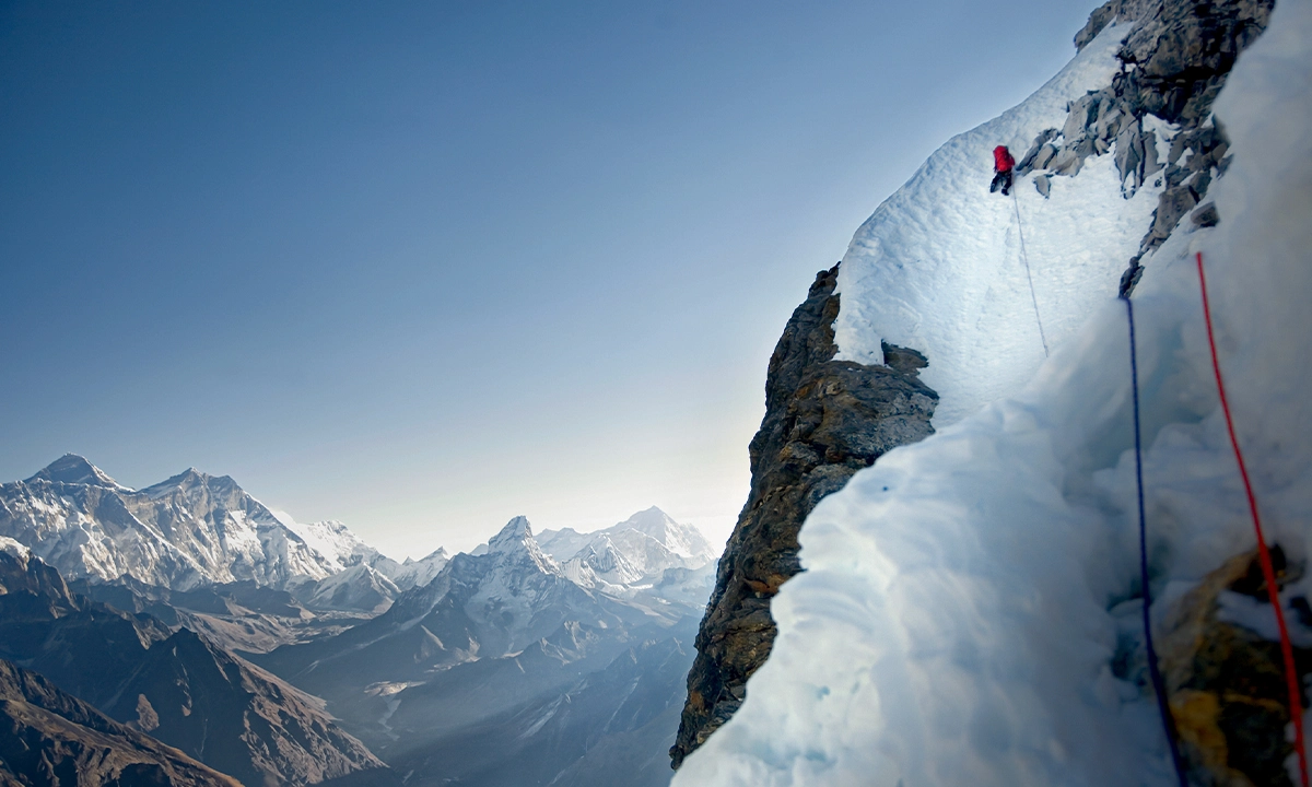 Ines Papert achève une traversée lors de la première ascension de Cobra Norte en face nord du Kwande Shar, au-dessus de la vallée du Khumbu. Sur l'horizon, se dressent, de gauche à droite, l'Everest, le Lhotse, l'Ama Dablam et le Makalu.
